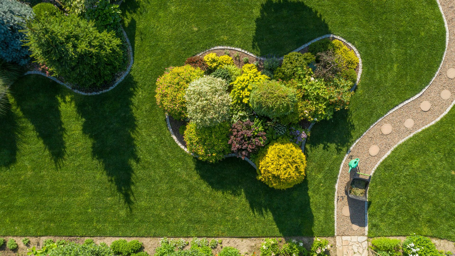 Aerial view of beautifully landscaped garden with green lawn and plant beds