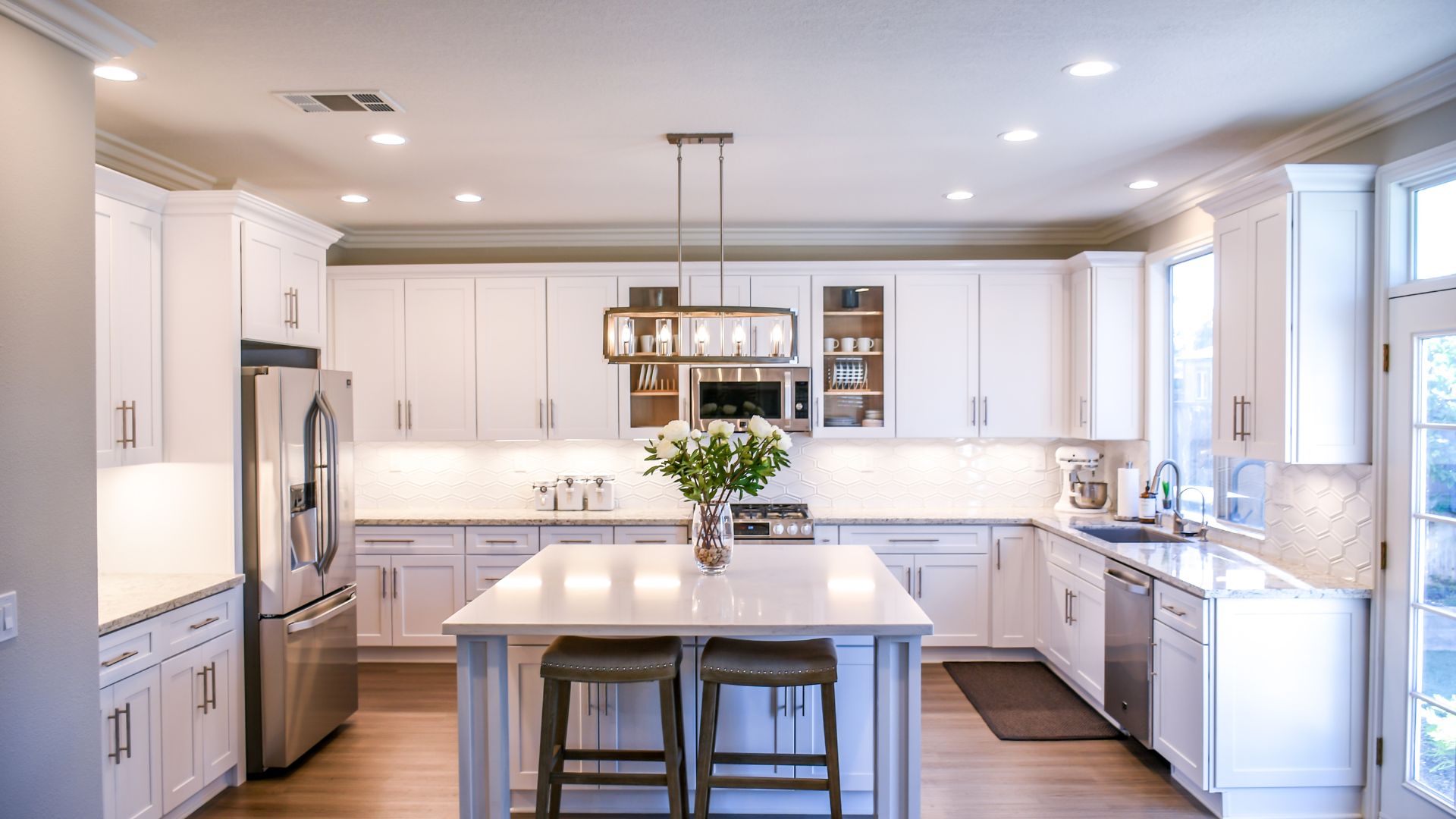Modern white kitchen with island, bar stools, and pendant light fixture