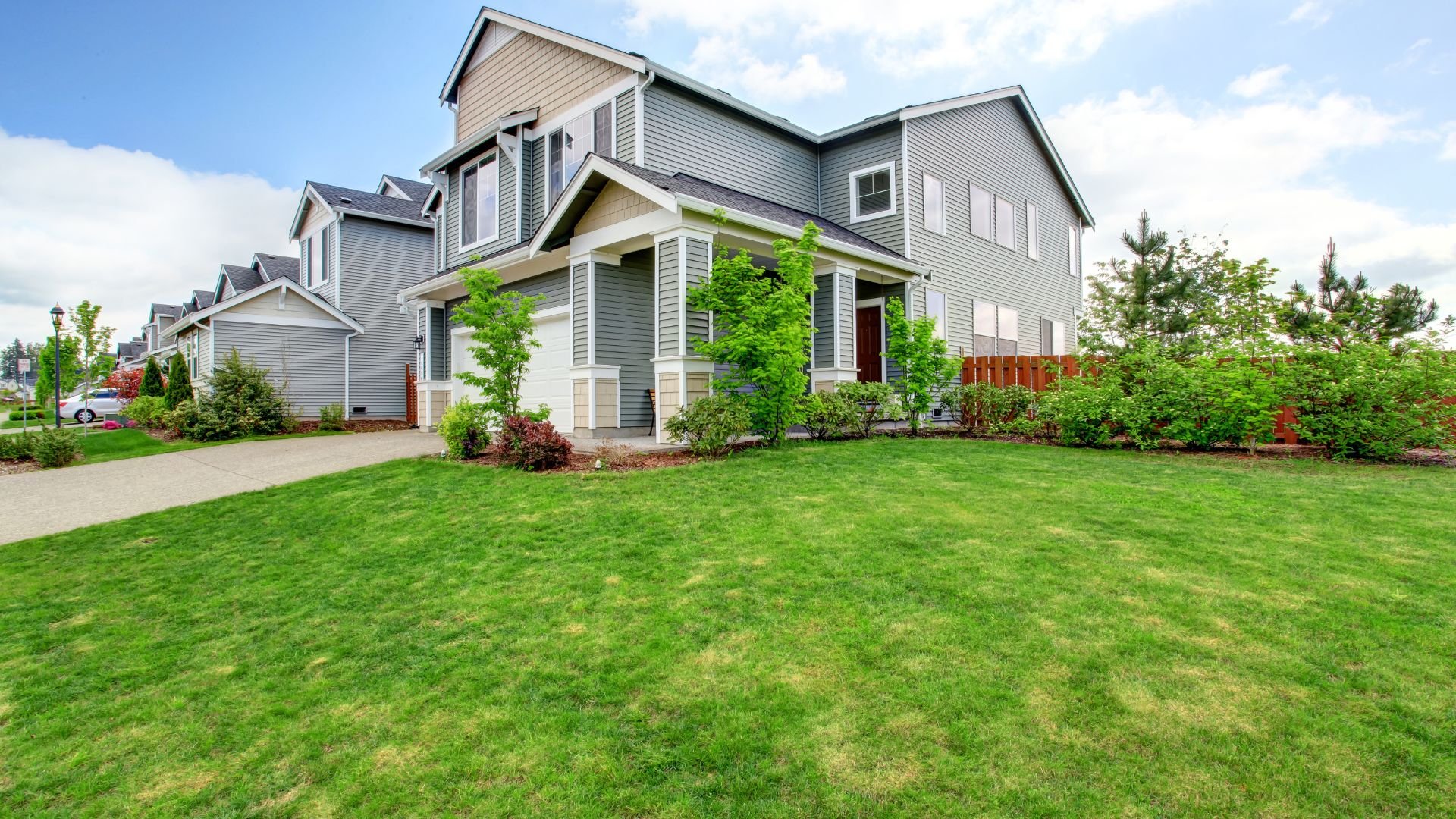 Modern two-story suburban house with green lawn and landscaped yard