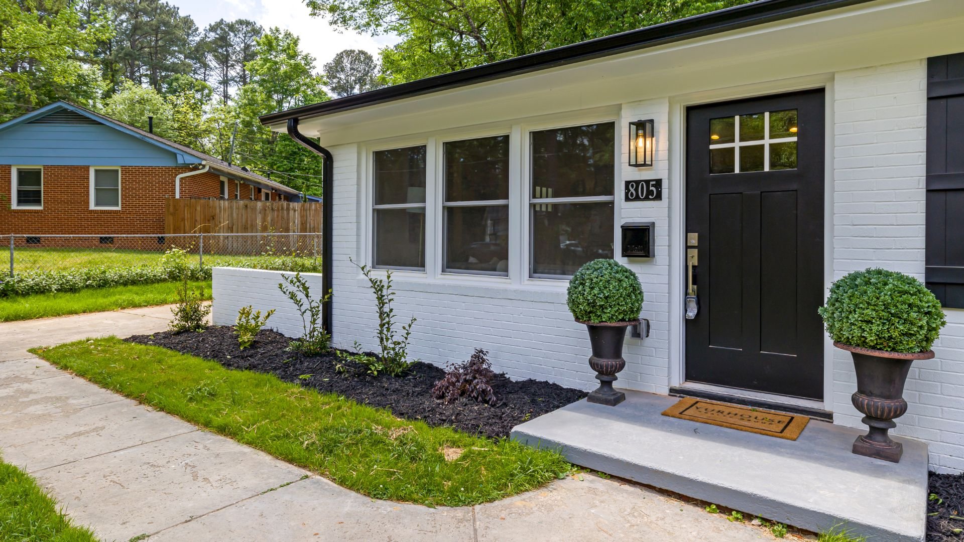 Modern white house with black door, potted plants, and welcoming front entrance